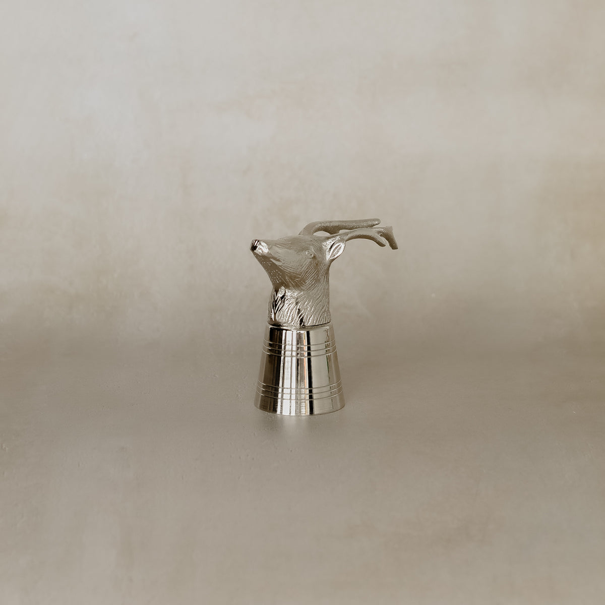 Silver deer-shaped object on a beige background