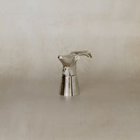 Silver deer-shaped object on a beige background
