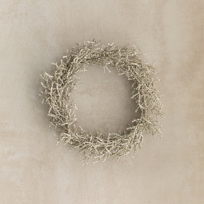Decorative wreath with glittery branches on a beige wall