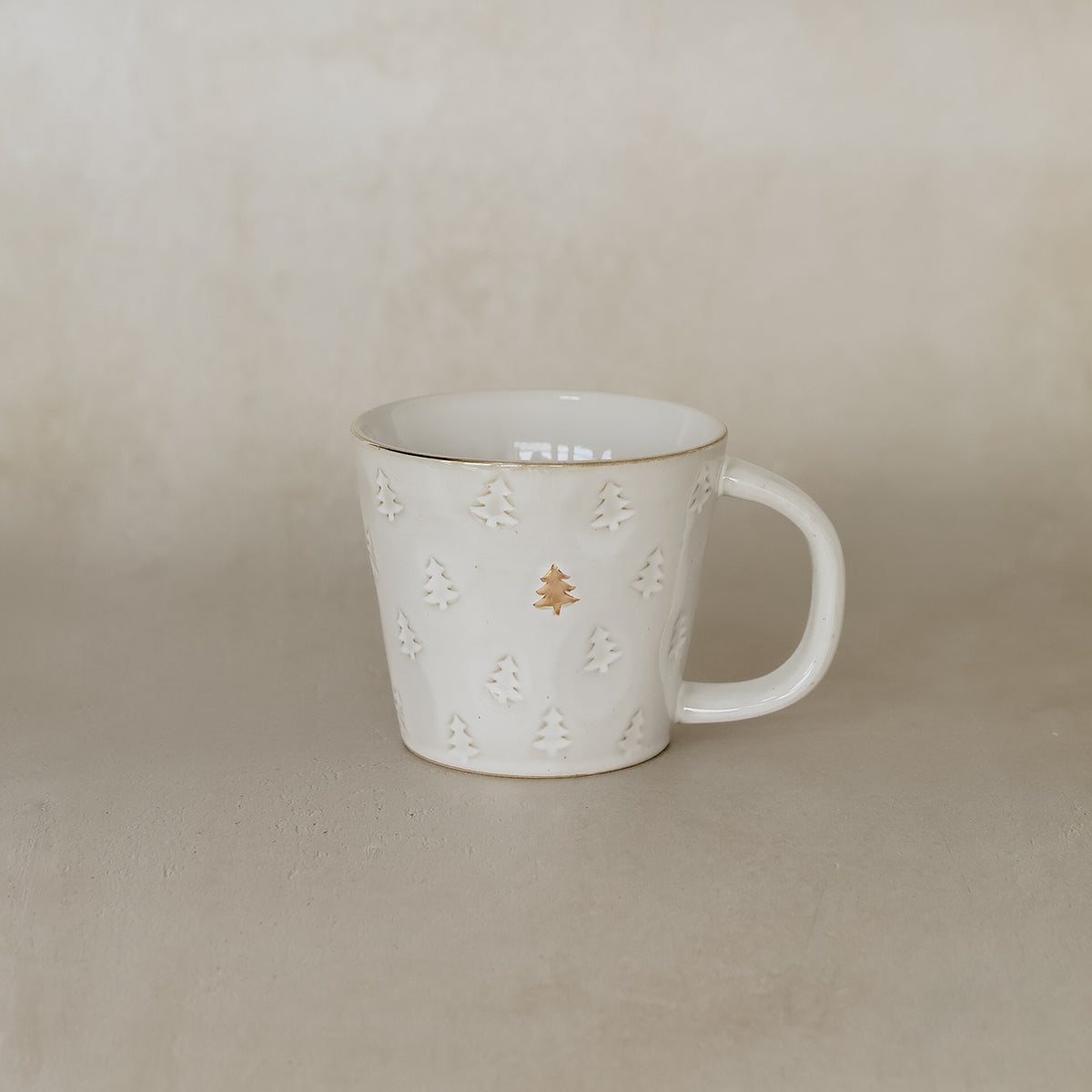 White ceramic mug with decorative elements on a beige background