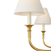 Acres Market & Interiors brass chandelier with six lights and white linen shades, classic design.